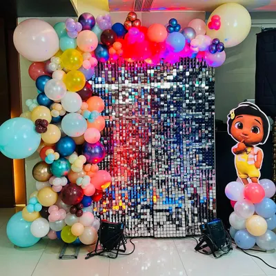 A shimmer wall backdrop is a versatile element that adds a touch of glamour to any theme. Here, it's framed by a colorful organic balloon garland and paired with a character cutout for a fun and festive photo booth area.