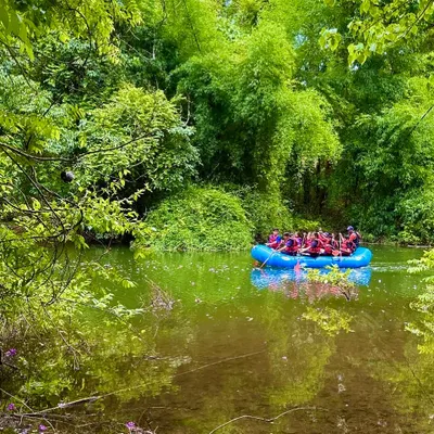 A raft full of young adventurers explores the calm, green backwaters of Shivpura. This serene environment is perfect for introducing children to rafting.