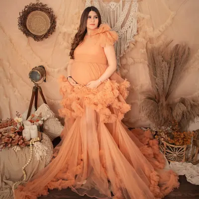 A stunning solo portrait in our boho-chic studio setup. The mom-to-be looks like a goddess in this elaborate peach ruffled gown, surrounded by soft, earthy tones.