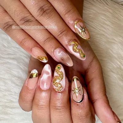 This set is pure magic. A soft nude and marble base on long almond nails provides the perfect canvas for sculpted 3D gold snakes with emerald green crystal eyes and celestial starburst accents.