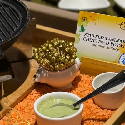 A modern take on a classic: Stuffed Tandoori Chettinad Potatoes served with a fresh coconut chutney, presented on a bed of red lentils for a dramatic effect.