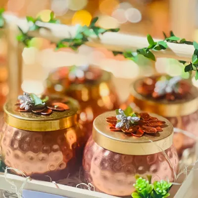 A close-up of my popular corporate gift: hammered copper jars in a wooden crate. The bokeh background highlights the premium feel of these gifts, perfect for employee appreciation or client thank yous.