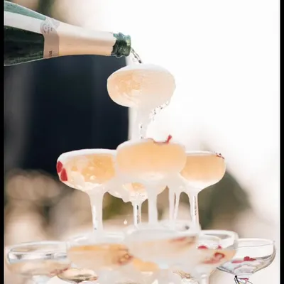 The perfect champagne pour. This close-up shot captures the moment a champagne tower comes to life, with bubbly overflowing into a cascade of celebration.