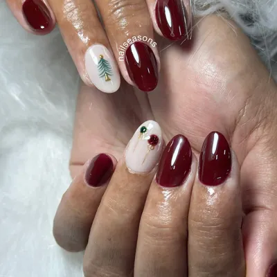 Getting into the festive spirit with this Christmas nail art. A deep, glossy maroon paired with a nude accent nail featuring a hand-painted Christmas tree and holly.