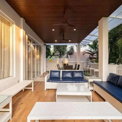 This terrace has a relaxed, coastal vibe. The white wicker furniture with deep navy cushions, a natural wood ceiling, and an open, breezy layout all come together to create a polished yet beachy atmosphere.