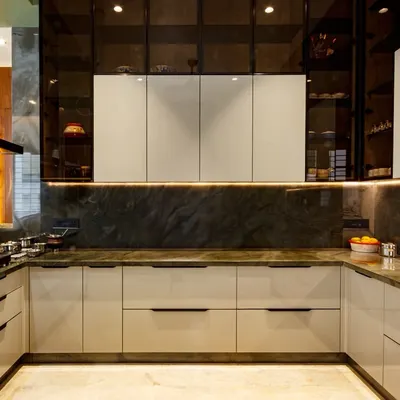 A frontal view of a modern show kitchen featuring turquoise green quartz countertops, white cabinets, and elegant overhead units with tinted glass.