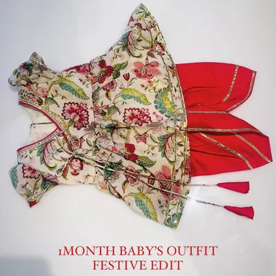 This complete festive set for a one-month-old baby includes a traditional floral print Angrakha top with tassel ties, paired with comfortable red dhoti pants finished with gota patti borders. It's designed for both style and comfort during family celebrations.