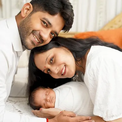 A perfect, peaceful newborn portrait. This close-up shot shows the baby sleeping soundly, nestled between his parents in a clean, white setting that emphasizes their connection.