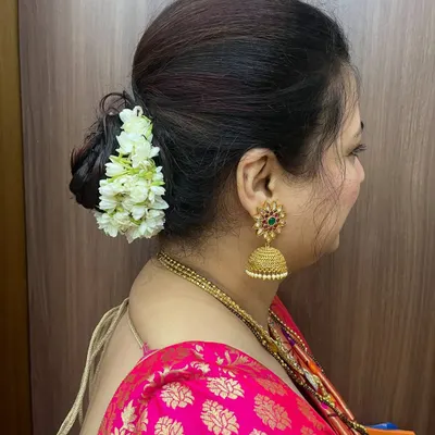 A classic and elegant low bun adorned with a fresh mogra gajra. This timeless hairstyle is perfect for pairing with a traditional saree.