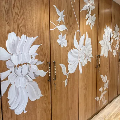 A full view of a series of wardrobe shutters hand-painted with a continuous design of white wildflowers. This project turns a functional storage unit into a seamless, flowing piece of botanical art.