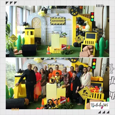 A full view of our construction-themed party for Aryaveer's 2nd birthday. The setup includes a city skyline backdrop, custom props, and a fun "Dig In" sign, with the family posing for a photo.