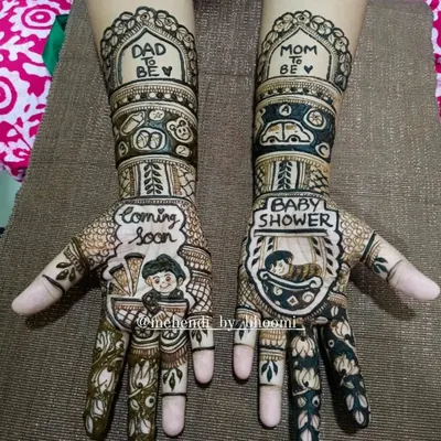 This baby shower mehendi was so much fun to create. It features "Coming Soon" and "Baby Shower" text, along with cute baby figures, a pram, and "Mom to be" and "Dad to be" messages.