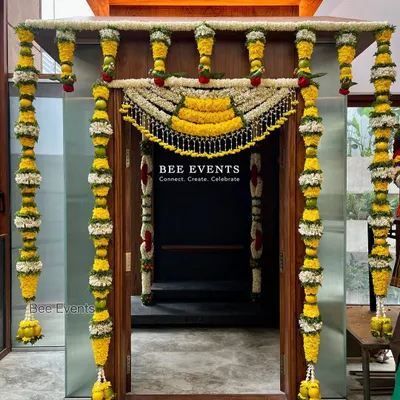 Traditional decor is our all-time favorite. This beautifully decorated pooja room entrance features intricate 'thomala' made from fresh flowers, creating a sacred and welcoming feel for a housewarming ceremony.