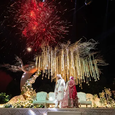 A truly explosive celebration of love under the night sky. I designed this Varmala moment with a stunning 'tree of life' mandap and a backdrop of dazzling fireworks, creating a memory that will last a lifetime.