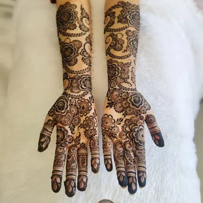 This is a perfect example of a full bridal Arabic henna for Madhia. The design features large, bold floral and paisley patterns that flow beautifully from the hands all the way up the arms.