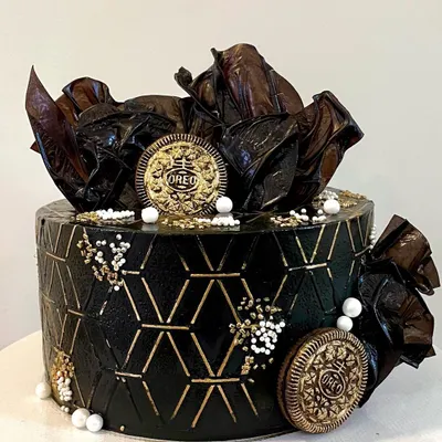 This design is all about texture and contrast. I used a geometric stencil on black buttercream to create a modern pattern, highlighted with gold. The cake is topped with abstract chocolate sails and gold-dusted Oreo cookies for a truly unique look.