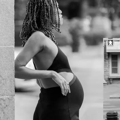 A black and white shot from an urban maternity session. The strong lines of the city architecture and the subject's confident pose create a powerful and modern portrait.