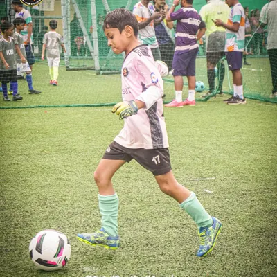 A young goalkeeper in control, dribbling the ball upfield. We train every player to be comfortable and skilled with the ball at their feet.