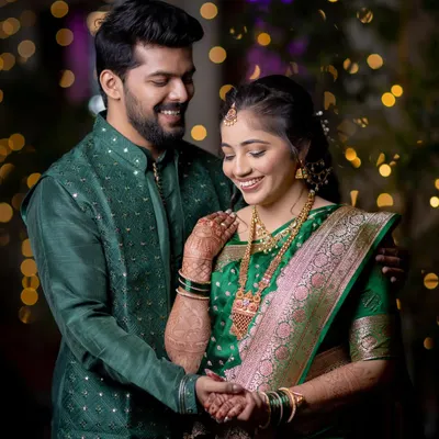 A joyful and candid moment from a ring ceremony. The genuine smiles and beautiful traditional attire are captured against a backdrop of sparkling lights.