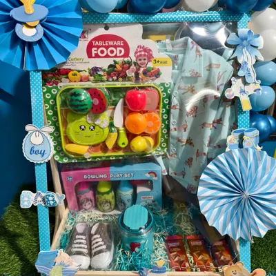 A fantastic first birthday hamper for a boy, decorated in blue. It's packed with a new outfit, toy shoes, a bowling set, and a fruit cutting toy set.