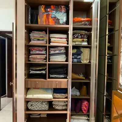 This image displays a fully customized wardrobe interior designed for maximum utility. It features a combination of open shelving for neatly stacked clothes, smaller cubbies for accessories, and deep drawers for concealed storage, ensuring a place for everything.