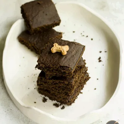 A stack of my rich and fudgy carob brownies for dogs. They have a wonderful texture and are made with simple, safe ingredients. I love topping them with a tiny bone biscuit for that extra touch of cute.