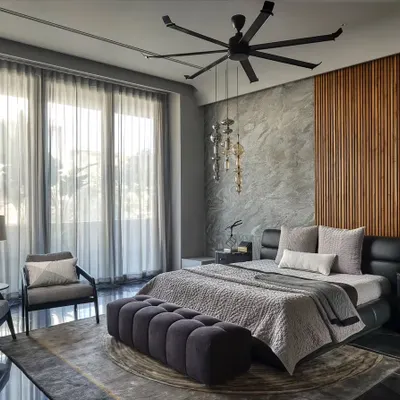 This tranquil master suite is designed for comfort and luxury. The material palette of grey stone, warm wood paneling, and soft textiles creates a serene atmosphere, while large windows offer an open view and abundant natural light.