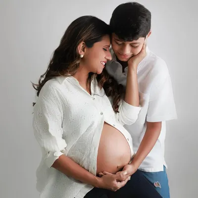 Welcoming a new chapter. This beautiful maternity portrait shows an expecting mother and her son sharing a tender moment, excited for the new arrival.