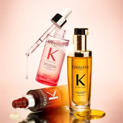 A stunning product shot of the Kérastase Genesis and Elixir Ultime serums, floating against a pink background. These are perfect for nourishing and strengthening your hair.