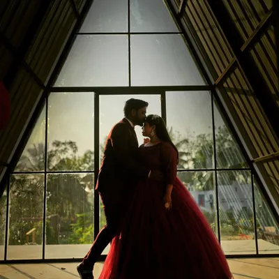 A silhouette of a couple against a modern A-frame window, creating a beautifully artistic and intimate pre-wedding photograph.