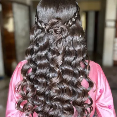 A truly romantic and intricate hairstyle. This look features a beautiful rose made from the client's own hair, surrounded by soft curls and delicate pearl accents. It’s a perfect hairstyle for an engagement or reception.