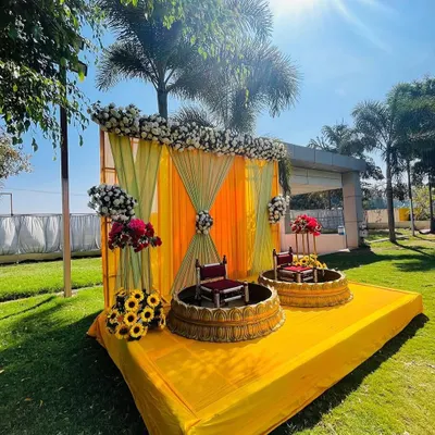 An outdoor Haldi stage setup under the bright sun. I used a combination of yellow and light green drapes with floral arrangements and traditional seating to create a picture-perfect ceremony space.