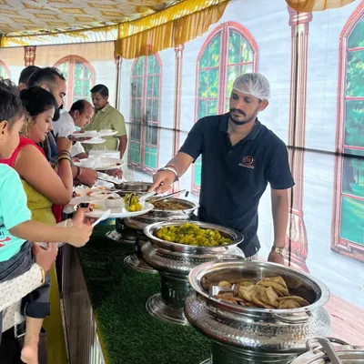 My team member serving a variety of pure vegetarian dishes at a house party. I ensure the buffet line moves smoothly so guests can enjoy their meal without a long wait.
