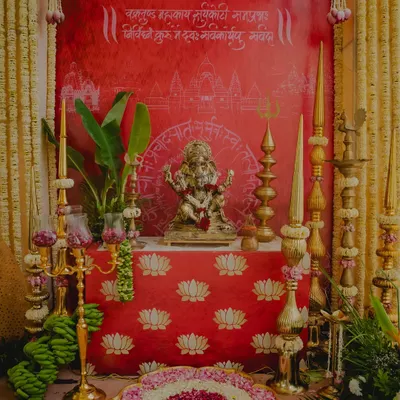 A sacred corner dedicated to Lord Ganesha, decorated in a traditional South Indian style with brass lamps, banana bunches, and a backdrop with Sanskrit verses.