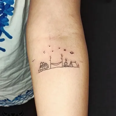 A tiny, single-line camping scene that tells a big story of adventure. This minimalist tattoo captures the joy of the outdoors, complete with a van, hammock, and campfire under the stars.
