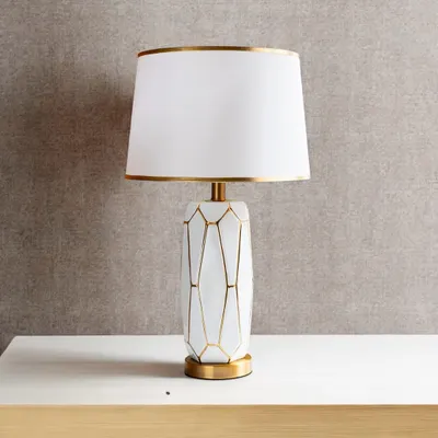 I love the simple elegance of this lamp. The white ceramic base features a geometric pattern outlined in gold, and the clean white shade is also trimmed in gold for a cohesive, luxurious feel. It's a perfect modern glam accent.
