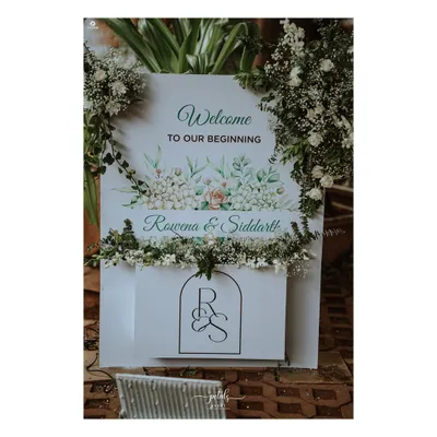 A beautiful welcome sign for a Christian wedding, featuring a watercolor floral design and the couple's custom monogram. The sign is adorned with fresh baby's breath, creating a soft and romantic entrance.