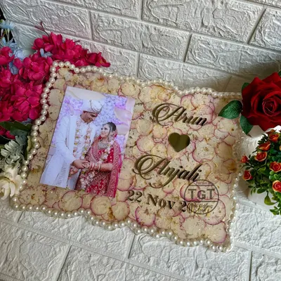A beautiful 12x16 inch rectangular resin frame preserving a couple's wedding photo and varmala petals. The border is lined with pearls from the original garland.