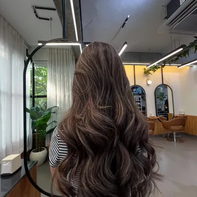 A full view of this gorgeous brunette balayage, styled with loose waves to showcase the seamless blend of light and dark tones. This is a perfect example of a low-maintenance, high-impact lived-in color.