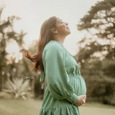 A moment of pure bliss during an outdoor maternity shoot. With her eyes closed and face turned to the sun, she soaks in the peacefulness of this fleeting time.