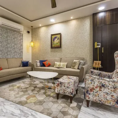 This living room is built on a neutral foundation with a comfortable beige sofa, allowing the accent pieces to shine. A bold, floral-printed wingback chair and colorful cushions add personality, while a geometric rug ties the entire seating arrangement together.