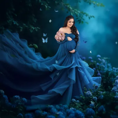 This breathtaking blue gown with a long, flowing trail is a favorite for creating magical, outdoor-inspired portraits. The off-shoulder lace sleeves add a touch of elegance to this maternity look.
