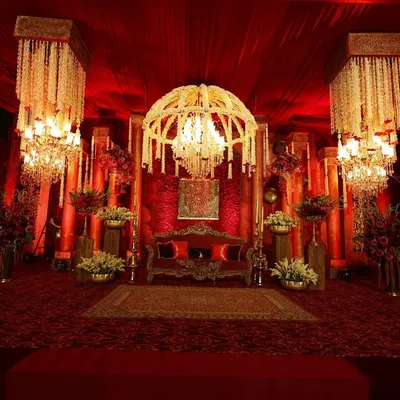 I designed this stage to be a regal masterpiece, with a majestic floral chandelier as the centerpiece, casting a warm glow over the rich red velvet settee and antique-inspired decor.