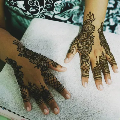 A complete bridal mehendi look, featuring symmetrical floral patterns that extend from the wrist to the fingertips. This traditional Indian henna style is perfect for creating a memorable and elegant statement on your wedding day.