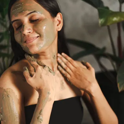 A perfect shot for a skincare campaign, showing a model enjoying the feeling of a clay mask. Her serene expression and the natural setting convey a sense of wellness and self-care.