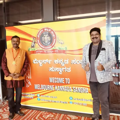 At the Melbourne Kannada Sangha event in Australia. I am standing next to the welcome banner, all set for the program to begin.