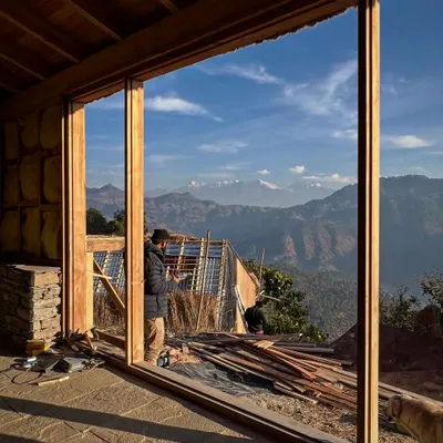 A view from inside one of our guesthouses in Vasudev, Uttarakhand. The large timber-framed window is designed to perfectly capture the breathtaking panorama of the Nanda Devi and Panchachuli peaks, making the landscape the central focus of the interior space.