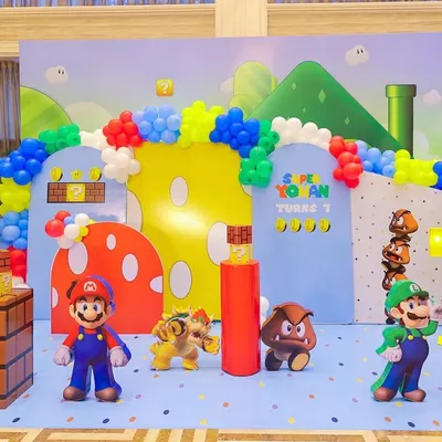 Welcome to the Mushroom Kingdom! This complete Super Mario stage setup features character cutouts of Mario, Luigi, Bowser, and Goombas, along with iconic game elements like warp pipes, question blocks, and a vibrant balloon arch.