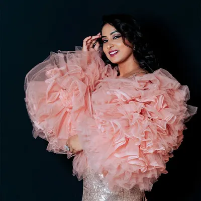 A portrait that balances elegance and confidence. The composition focuses on the model's expression and the voluminous texture of the ruffled tulle jacket, making it a strong shot for a makeup artist's portfolio or a fashion feature.
