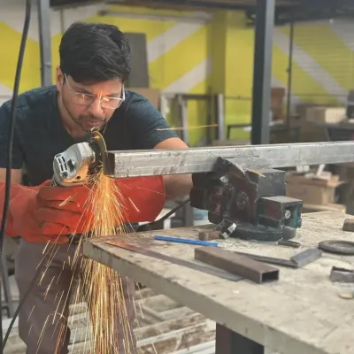 Total concentration while using an angle grinder to cut through a metal bar. Our workshops emphasize safety and precision, teaching you how to control the tools with confidence.